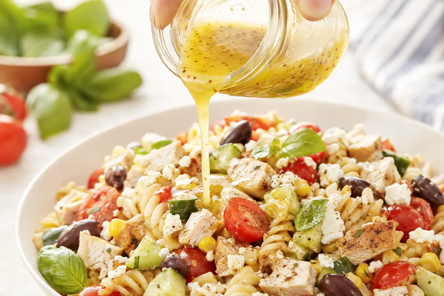 Vinaigrette au citron versée sur une salade de pâtes au poulet